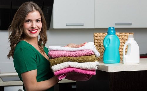 девушка улыбается и несет чистое цветное белье